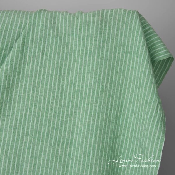 Wide washed green striped linen fabric close up edge view