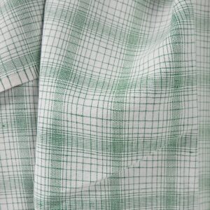 White linen cotton fabric with striped green checks close up view of pattern
