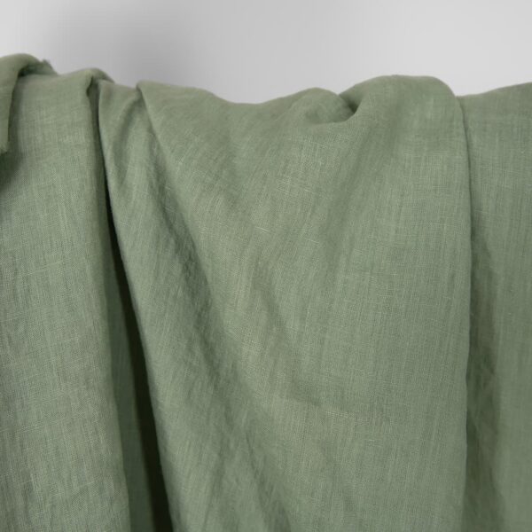 Washed linen fabric in muted light green, plain weave