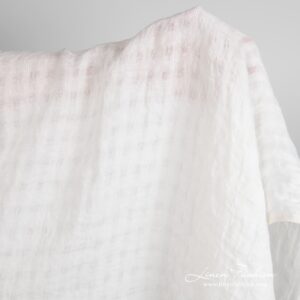 Luonnonvalkoinen pellavakangas läpikuultavin ruuduin pesty